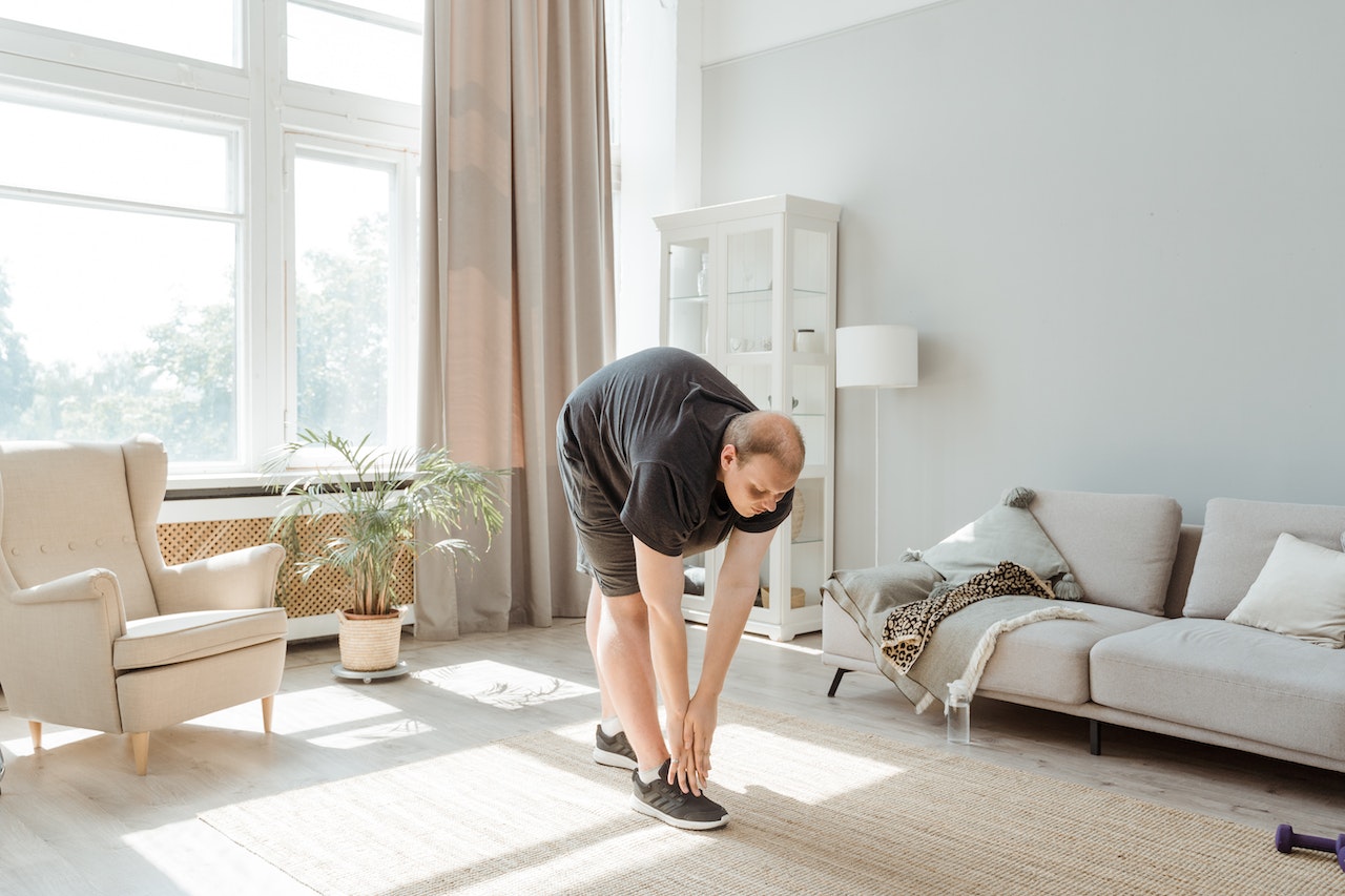 weight loss tips at home -man bending to touch toes doing exercise at home